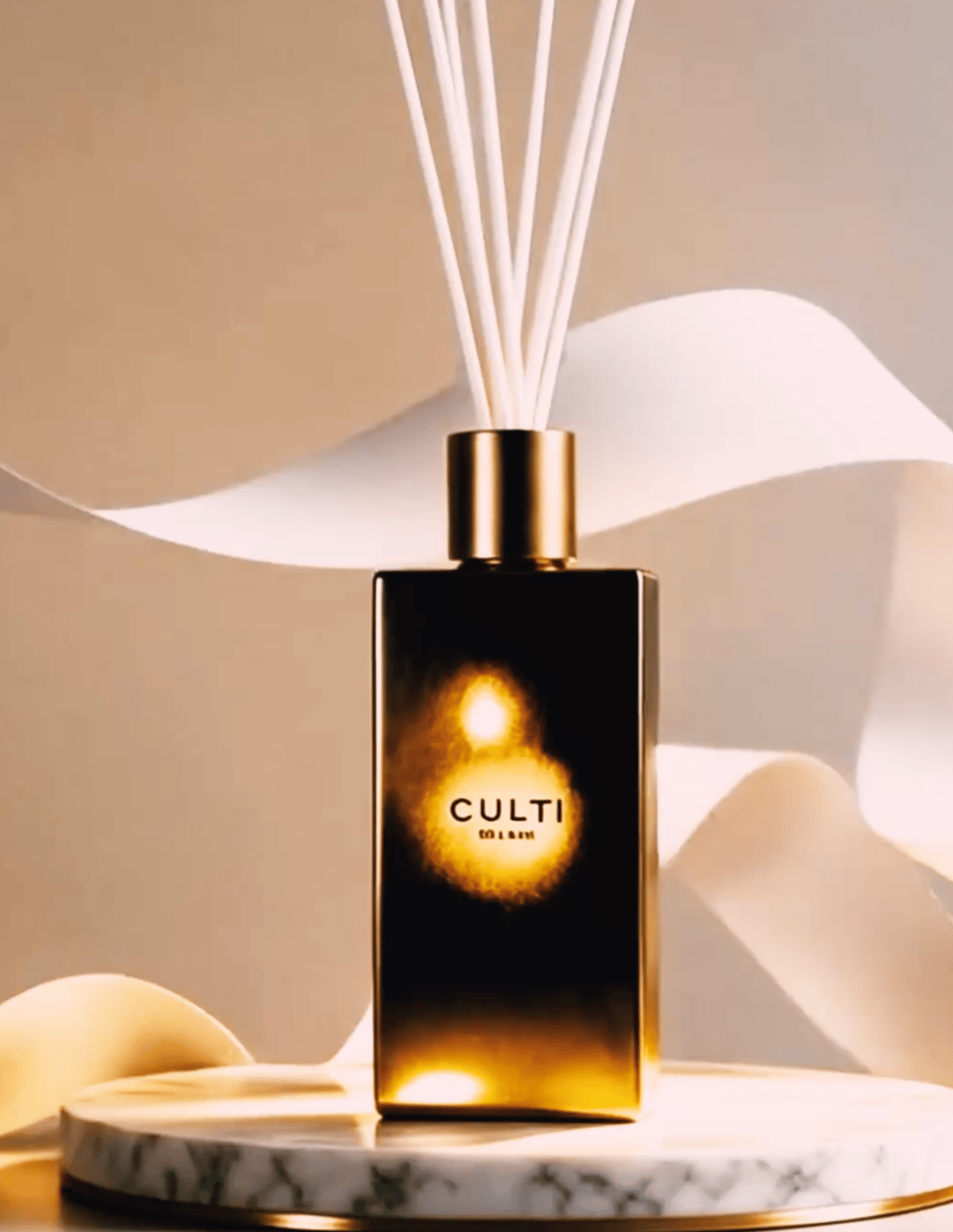 Part III: an amber glass reed diffuser glowing against sculptural white paper