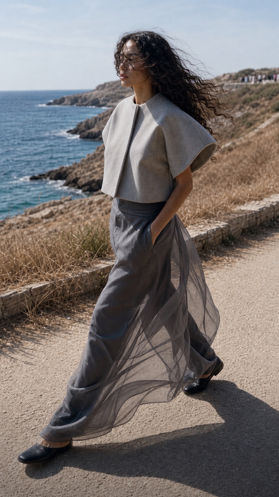 Leandra in side profile wearing summer wool and translucent silk by the coast